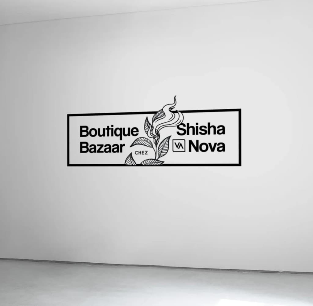 Horizontal Boutique Bazaar chez Shisha Nova logo as a black wall graphic on a white gallery wall, the botanical branch rising through the centre of the frame.