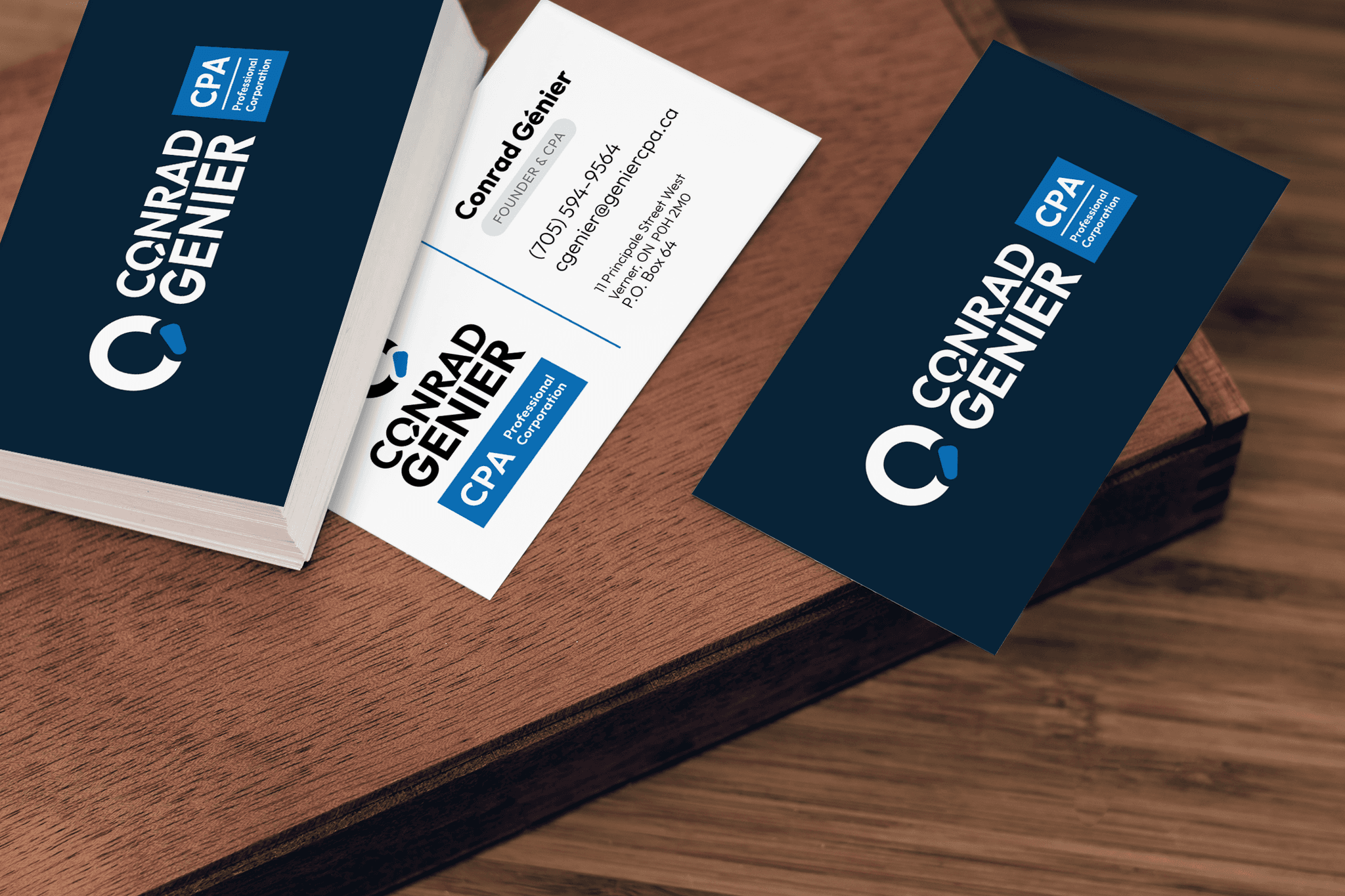 Conrad Genier CPA business cards on a wooden desk: navy cards with the white wordmark and circular C mark, and a white card showing contact details with a blue accent.