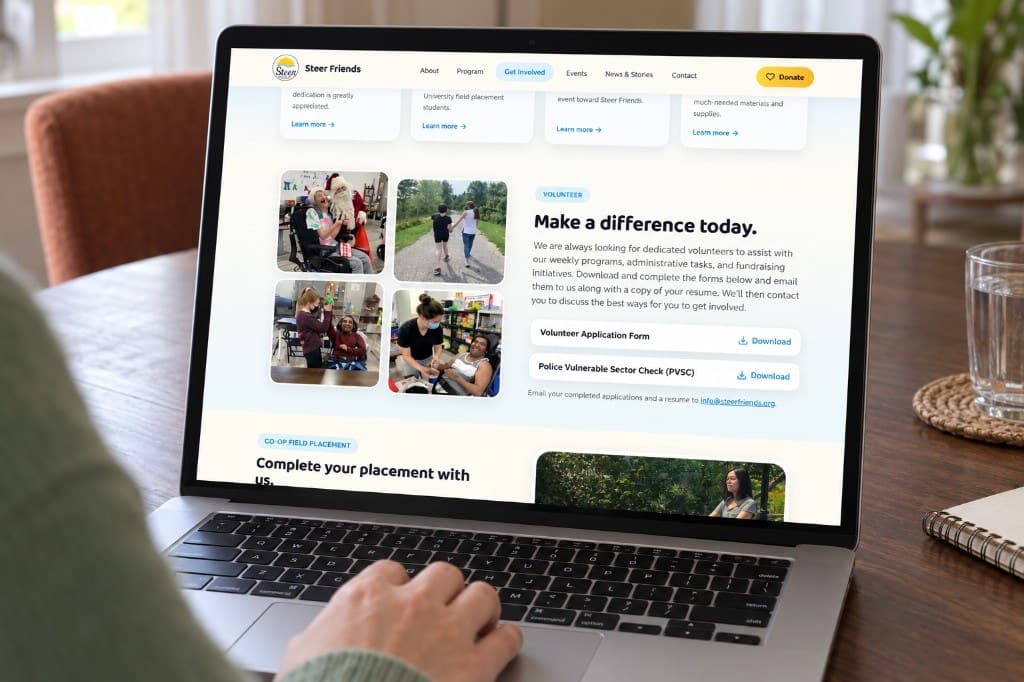 A laptop on a wood table showing a Steer Friends page with a photo grid on the left and a heading about getting involved on the right.