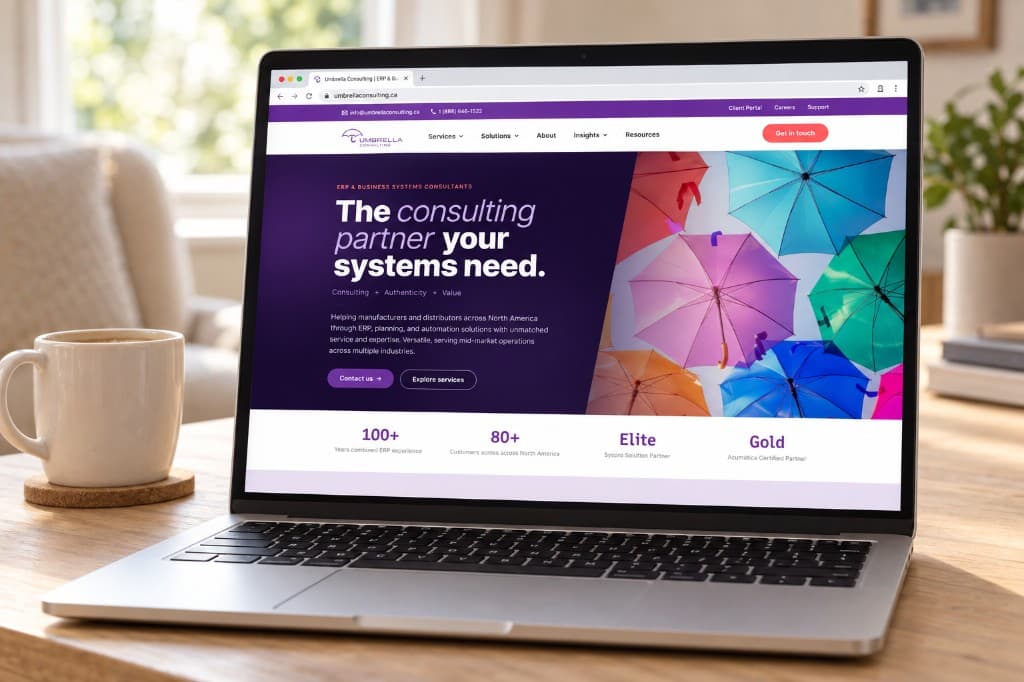 A laptop on a wood desk showing the Umbrella Consulting homepage: a dark purple hero beside a photograph of colourful umbrellas.