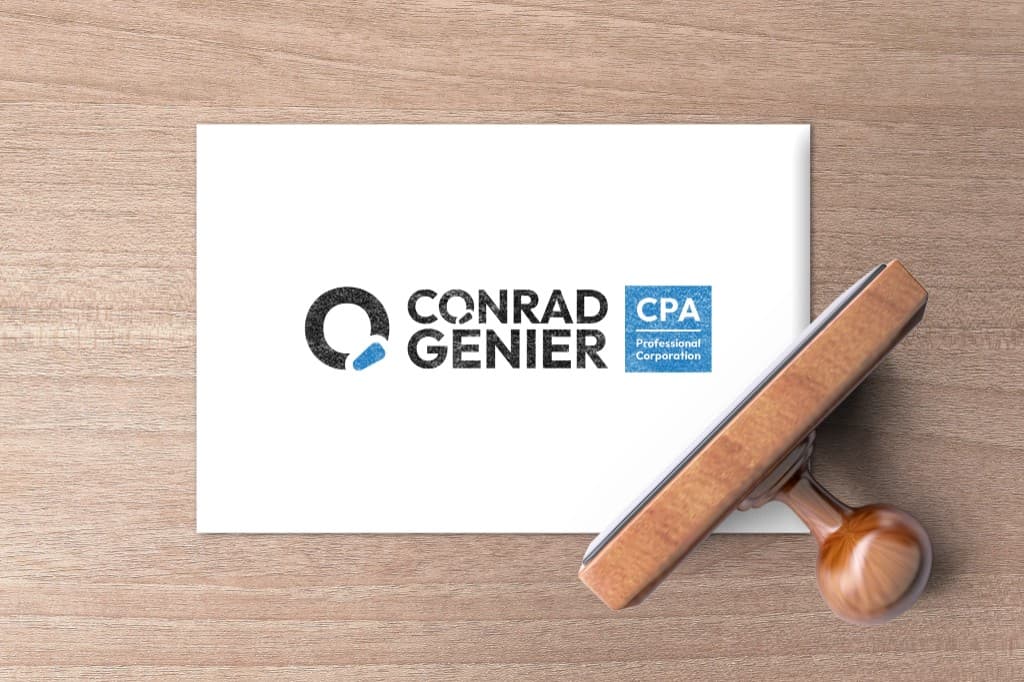 Horizontal Conrad Genier CPA logo stamped in black and blue ink on a white card, with a wooden rubber stamp resting beside it.