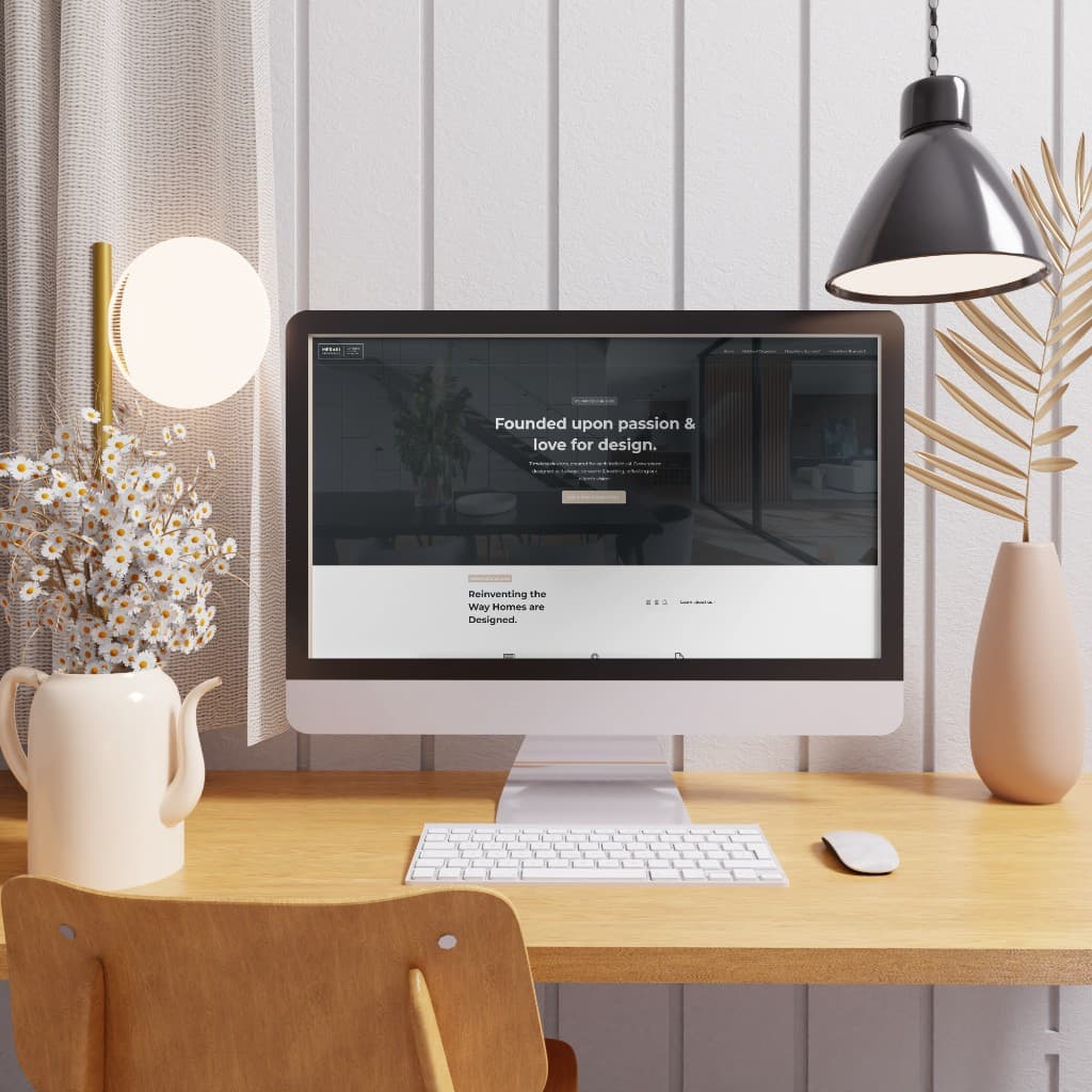 A desktop computer on a light wood desk showing a Meraki Design Co. homepage concept.