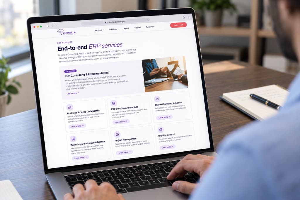 Someone using a laptop that shows the Umbrella Consulting services page: an introduction beside a photograph, and a grid of service cards.